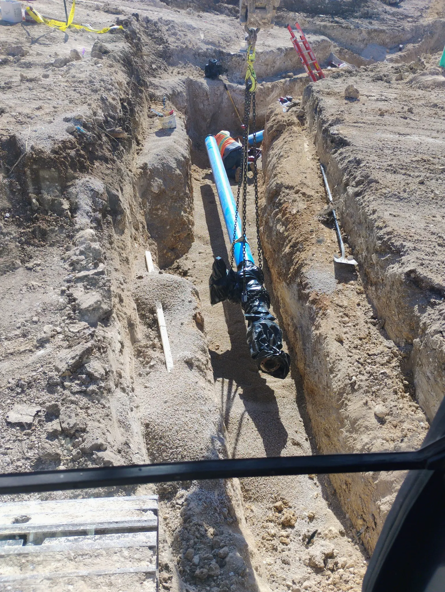 Construction site with exposed underground pipes and trench work.
