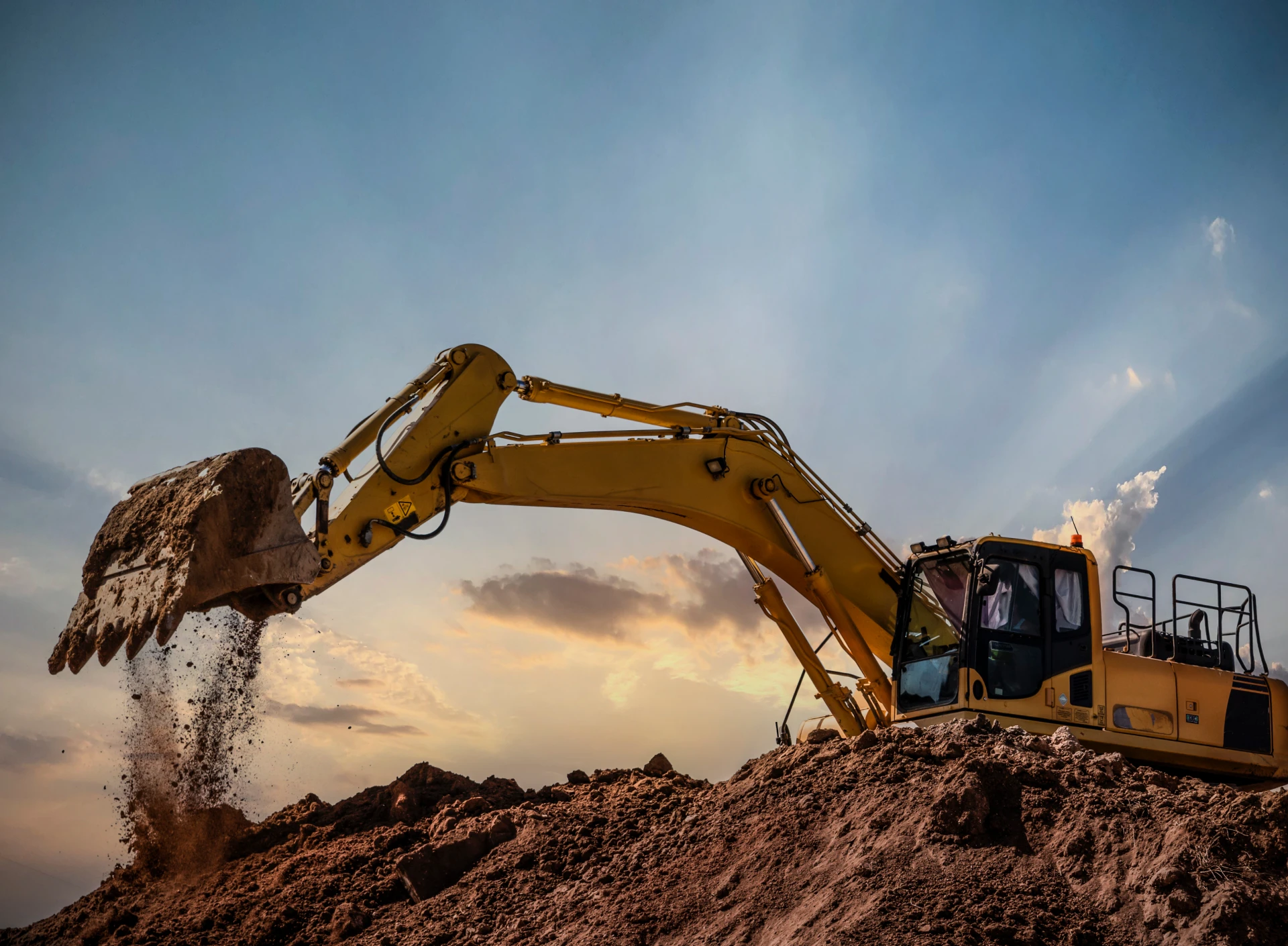 Excavator digging under sunset sky